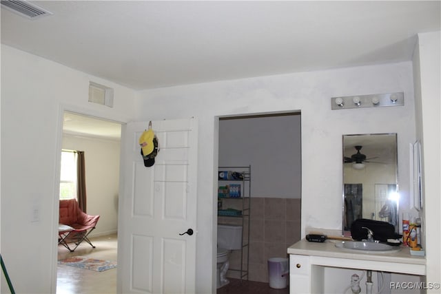 bathroom featuring vanity, toilet, tile walls, and ceiling fan