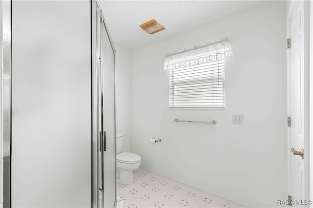 bathroom featuring a shower, a textured ceiling, and toilet