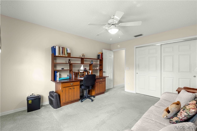 carpeted office space featuring ceiling fan and a textured ceiling