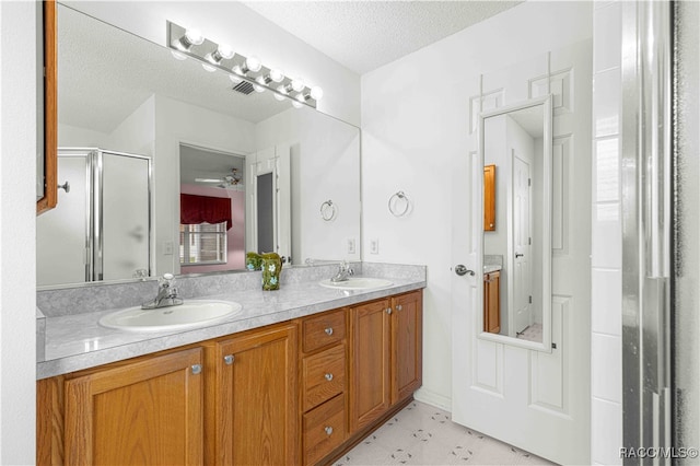 bathroom featuring ceiling fan, an enclosed shower, a textured ceiling, and vanity