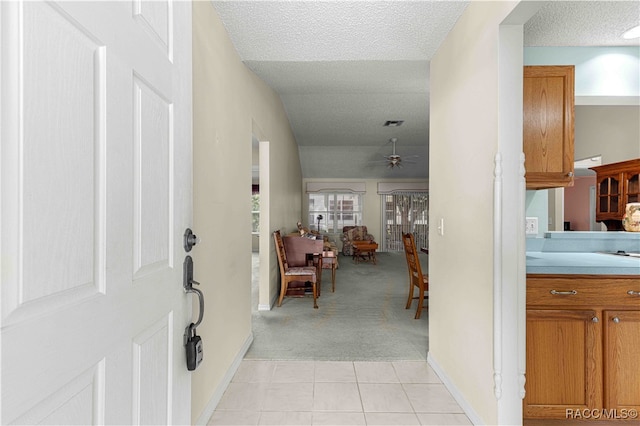 corridor with a textured ceiling and light colored carpet