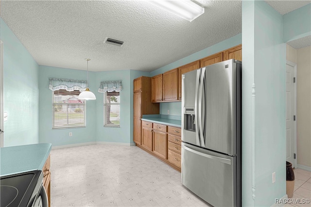 kitchen featuring a textured ceiling, hanging light fixtures, and appliances with stainless steel finishes