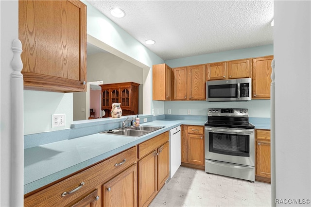 kitchen with kitchen peninsula, sink, a textured ceiling, and appliances with stainless steel finishes