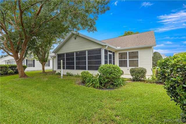 rear view of property with a sunroom and a yard