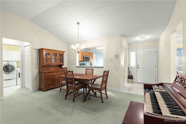 carpeted dining area featuring a textured ceiling, an inviting chandelier, vaulted ceiling, and washer / clothes dryer