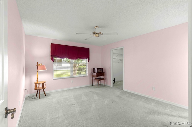 spare room featuring a textured ceiling, ceiling fan, and light carpet