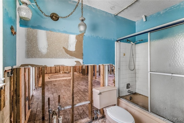 bathroom with toilet, a textured ceiling, and combined bath / shower with glass door