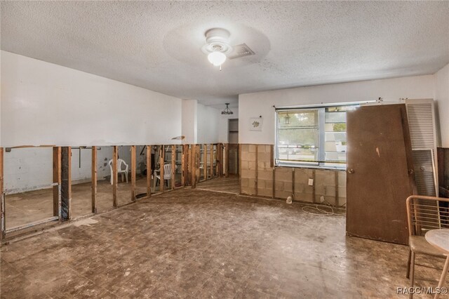 miscellaneous room with ceiling fan and a textured ceiling