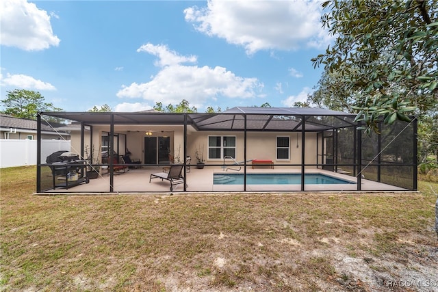 back of house with glass enclosure, a patio area, and a yard