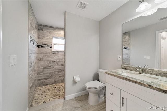 bathroom with toilet, vanity, and tiled shower