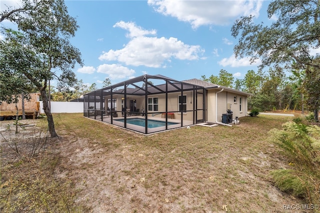 rear view of house with glass enclosure, a fenced in pool, and a yard