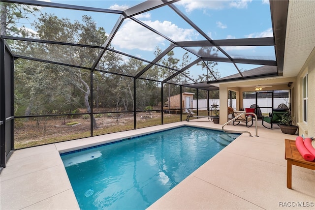 view of pool with a patio, glass enclosure, a shed, and ceiling fan