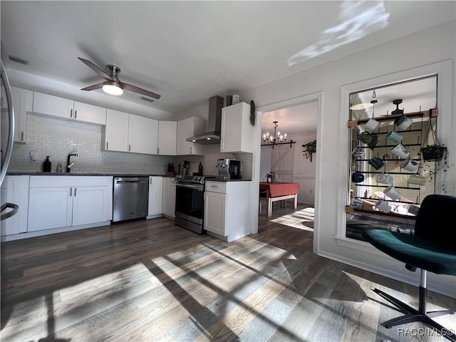 kitchen with appliances with stainless steel finishes, tasteful backsplash, white cabinetry, and wall chimney range hood