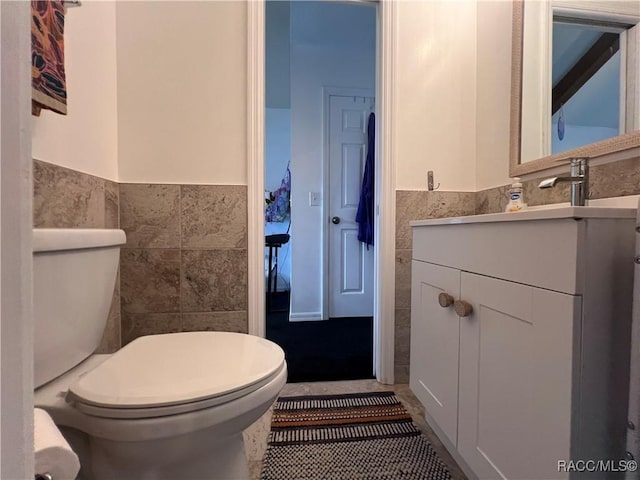 bathroom featuring vanity, tile walls, and toilet