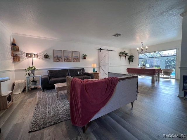 living room with an inviting chandelier, a barn door, hardwood / wood-style floors, a textured ceiling, and pool table