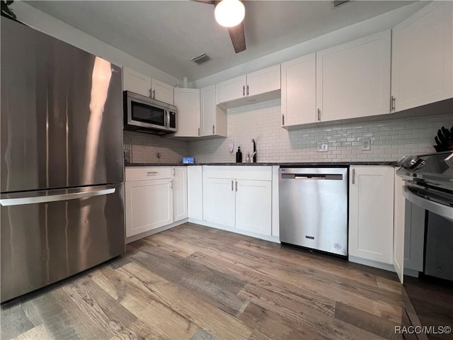 kitchen with white cabinets, sink, decorative backsplash, light wood-type flooring, and stainless steel appliances