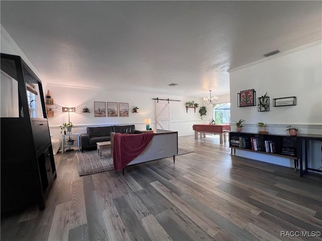 living room with a barn door, crown molding, a chandelier, and hardwood / wood-style flooring