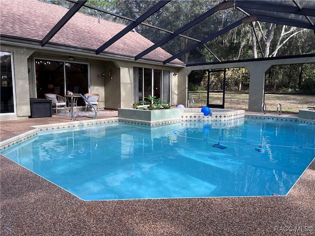 view of swimming pool featuring glass enclosure and a patio