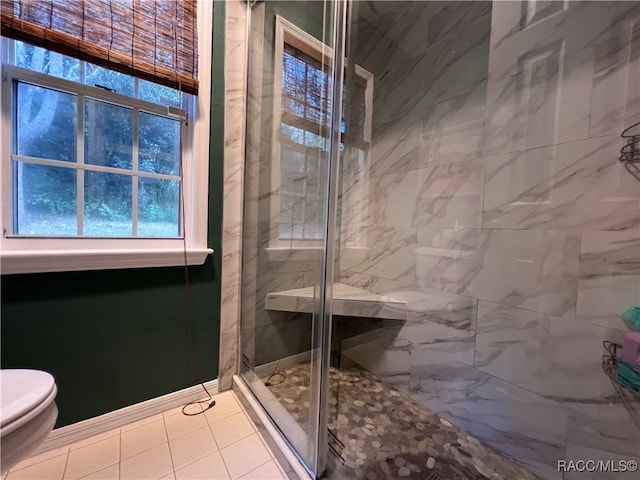 bathroom with an enclosed shower, toilet, and tile patterned floors