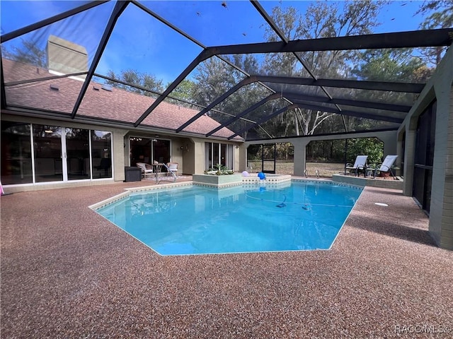 view of pool featuring glass enclosure and a patio