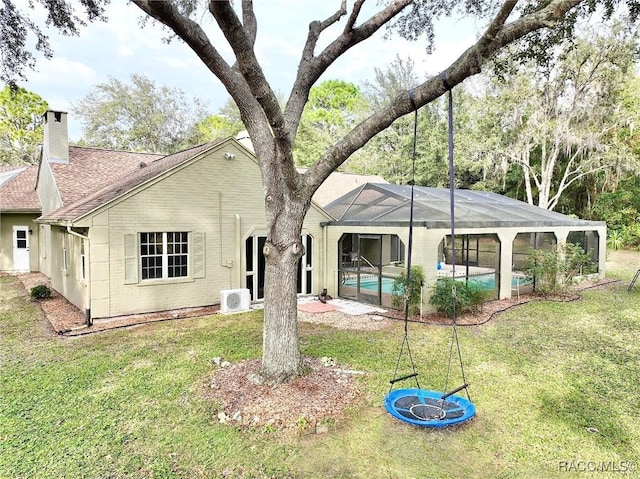 rear view of property with a lanai and a yard