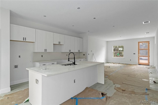 kitchen with sink, a kitchen island with sink, and white cabinets