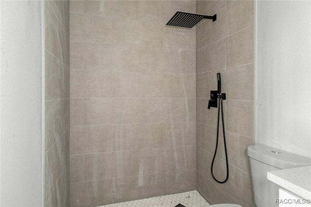 bathroom featuring vanity, toilet, and a tile shower