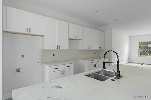 kitchen with light stone countertops, sink, and white cabinets