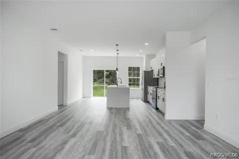 kitchen with a center island, light hardwood / wood-style flooring, appliances with stainless steel finishes, pendant lighting, and white cabinets