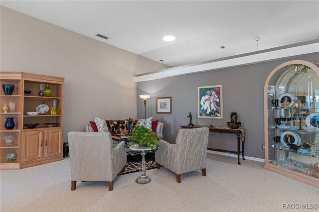 living area with baseboards, visible vents, and light colored carpet