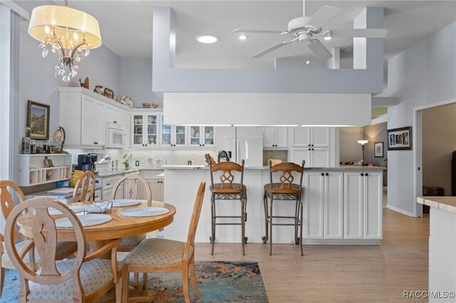 kitchen with white appliances, tasteful backsplash, white cabinets, glass insert cabinets, and a high ceiling