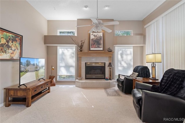 carpeted living room featuring plenty of natural light, baseboards, ceiling fan, and a tiled fireplace