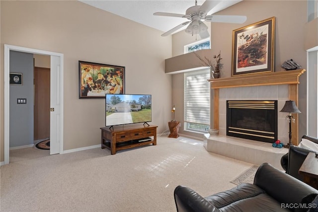 carpeted living room featuring a high ceiling, a tile fireplace, a ceiling fan, and baseboards