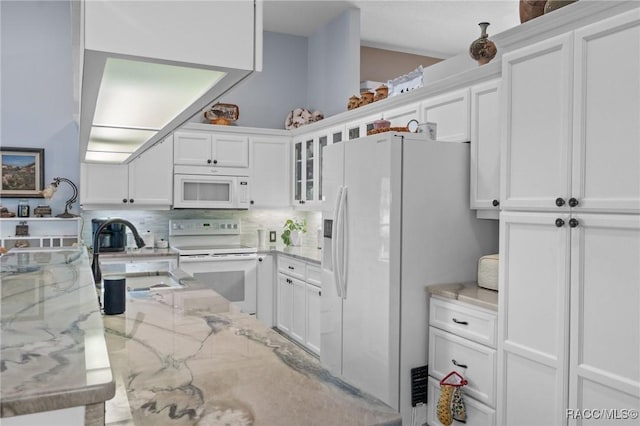 kitchen with white appliances, a sink, white cabinetry, tasteful backsplash, and glass insert cabinets