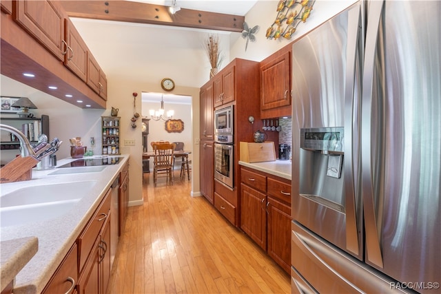 kitchen with sink, a notable chandelier, pendant lighting, appliances with stainless steel finishes, and light wood-type flooring