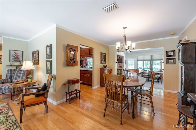 dining space featuring an inviting chandelier, ornamental molding, and light wood-type flooring