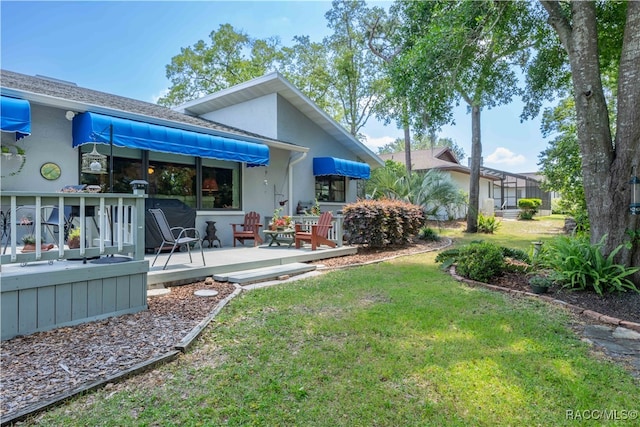 back of property featuring a wooden deck and a yard