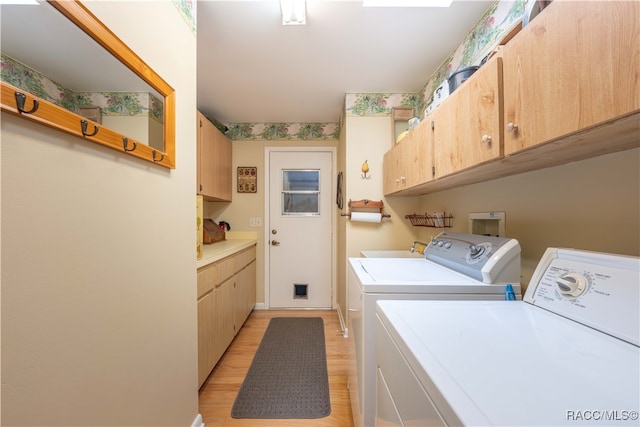 clothes washing area with cabinets, light wood-type flooring, sink, and washing machine and dryer