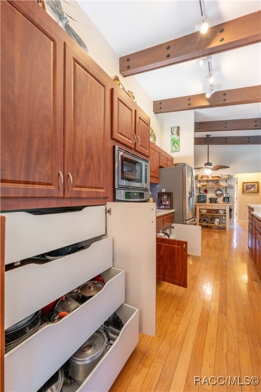 kitchen featuring beam ceiling, stainless steel microwave, light wood-type flooring, and track lighting