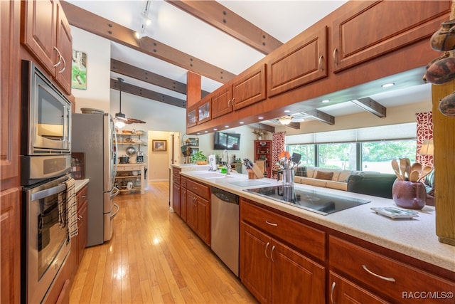 kitchen featuring ceiling fan, sink, stainless steel appliances, vaulted ceiling with beams, and light wood-type flooring