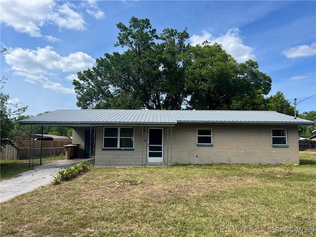 1029 NE 24th St, Ocala, FL 34470 - view of front facade with a front lawn, fence, concrete block siding, an attached carport, and concrete driveway