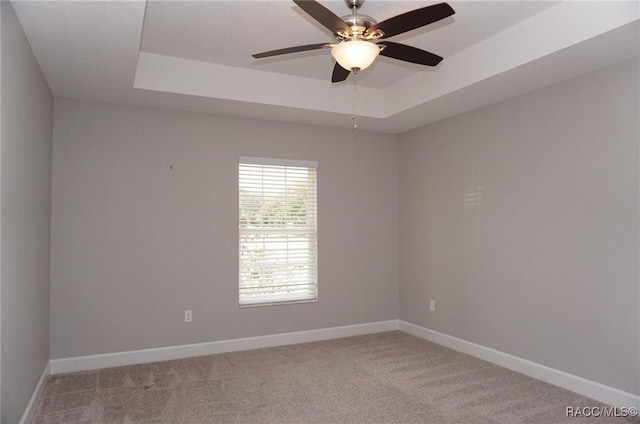 carpeted empty room with a tray ceiling and ceiling fan