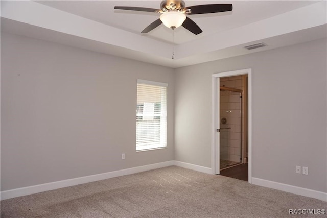 carpeted empty room featuring ceiling fan and a raised ceiling