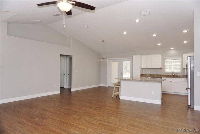 kitchen with a kitchen island, pendant lighting, wood-type flooring, lofted ceiling, and white cabinets