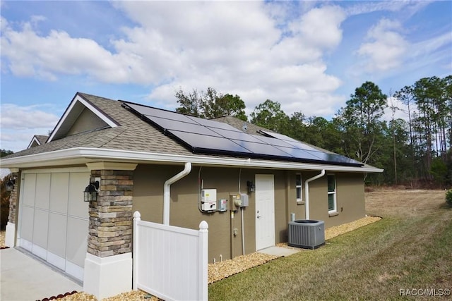 view of home's exterior featuring a garage, solar panels, a lawn, and central air condition unit