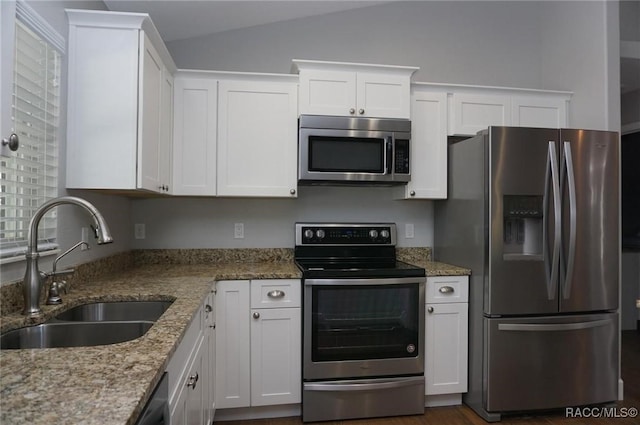 kitchen with lofted ceiling, appliances with stainless steel finishes, sink, and white cabinets