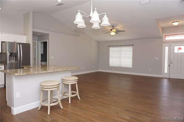 kitchen featuring hanging light fixtures, light stone countertops, white cabinets, a kitchen bar, and stainless steel fridge with ice dispenser