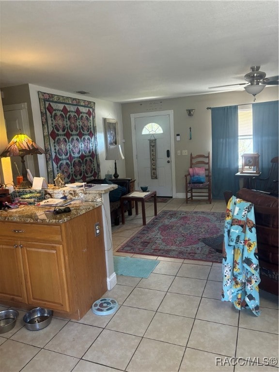 kitchen featuring light stone countertops, light tile patterned floors, and ceiling fan