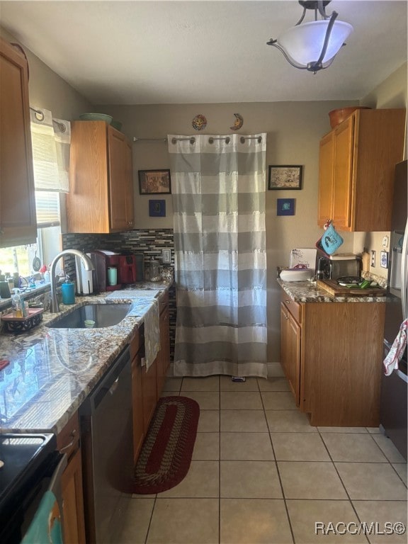 kitchen with light stone countertops, stainless steel dishwasher, sink, light tile patterned floors, and black / electric stove