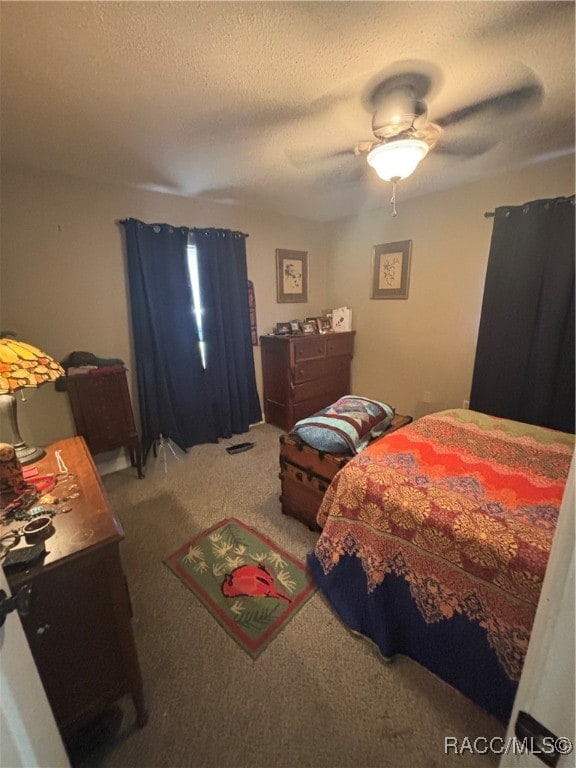 carpeted bedroom with ceiling fan and a textured ceiling